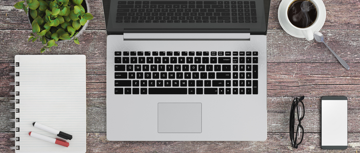 desk with notebook paper, laptop and coffee cup.