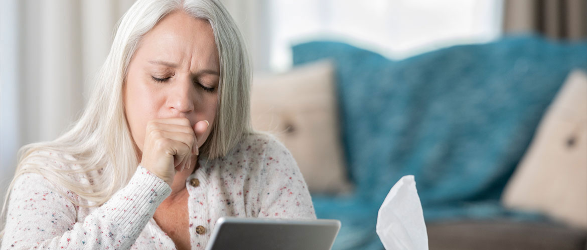 a woman coughing while holding a digital tablet