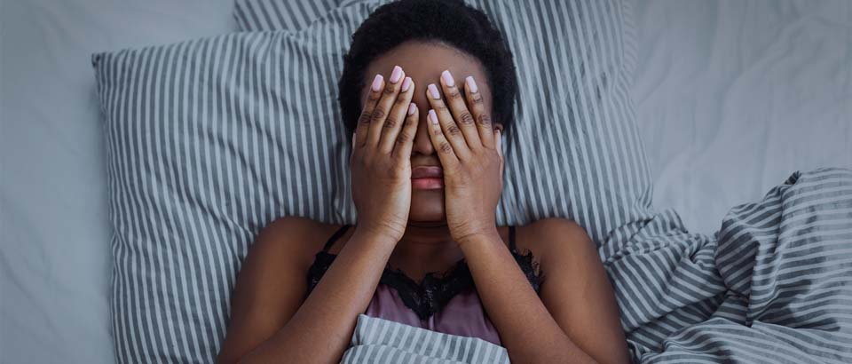 woman laying in bed with her hands on her head