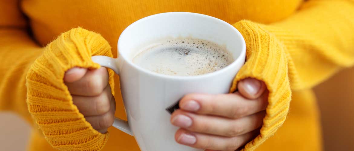 person holding a coffee cup in a yellow sweater