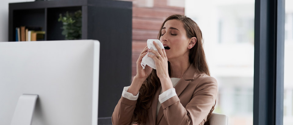 woman sneezing while sitting at her desk