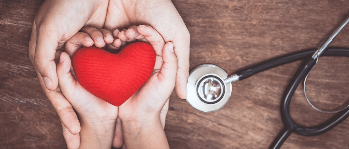 hands holding a fabric heart with a stethoscope nearby