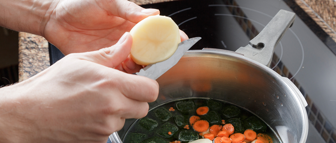 woman cooking vegetables in pot on stove